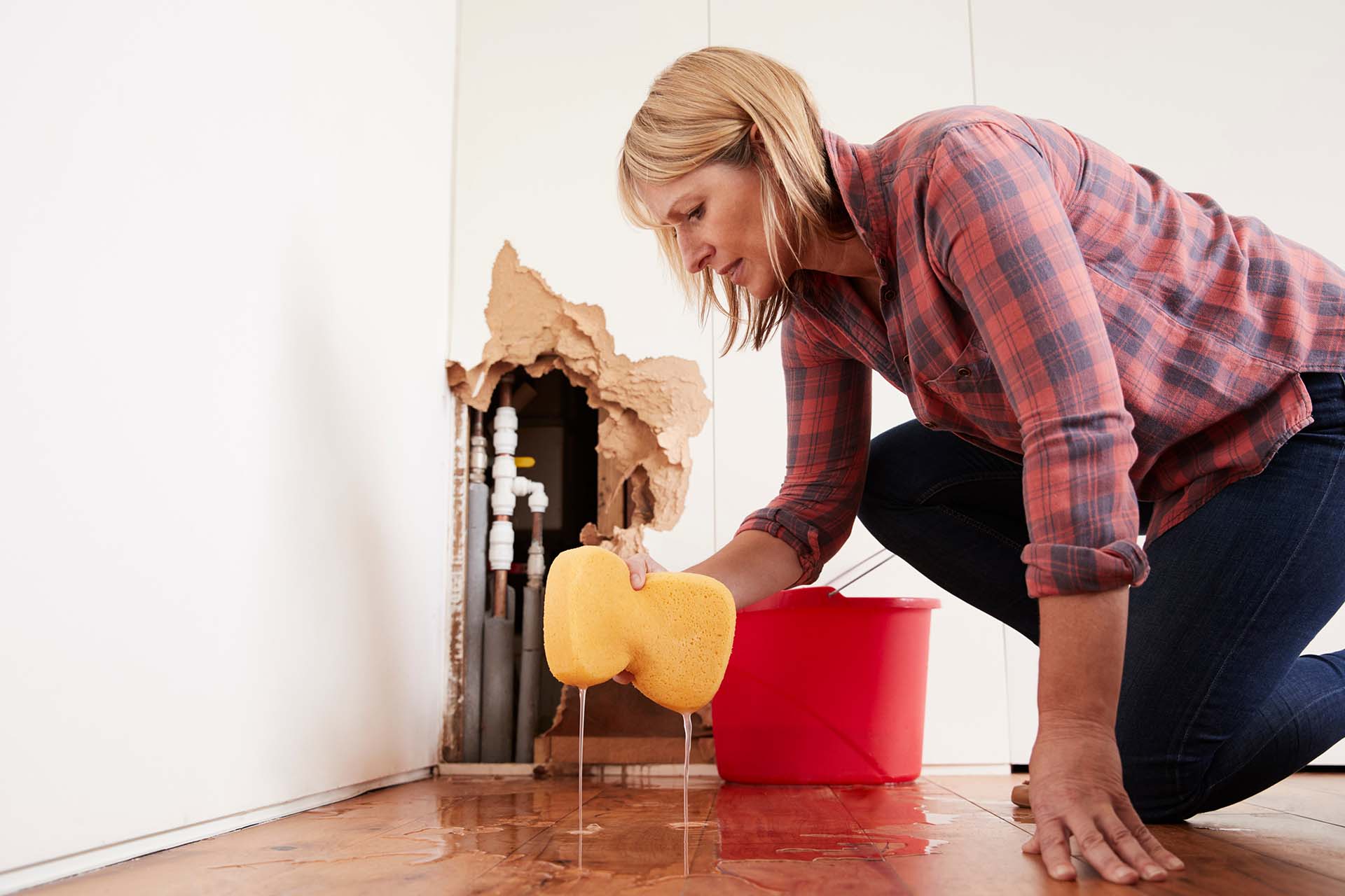 A woman kneeling on the floor, cleaning with a yellow sponge.