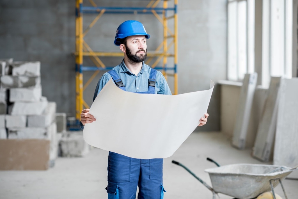 Construction worker holding a map in a concrete building.