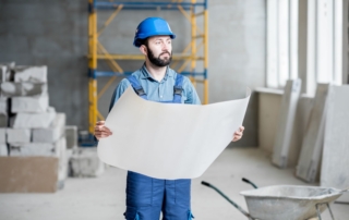 Construction worker holding a map in a concrete building.