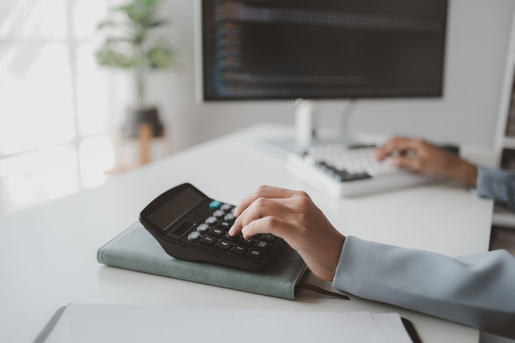 A partial view of a male accountant using estimating software on a computer, focusing on project costs.