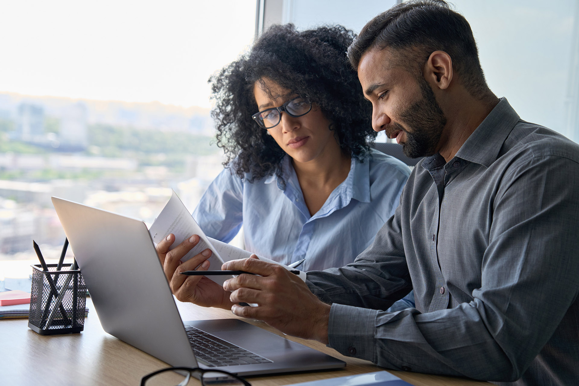 A man and woman sitting together, focused on a laptop screen.