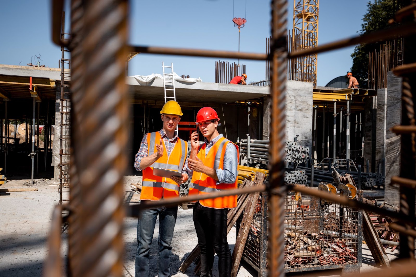 An architect and an engineer wearing orange work vests and helmets were assessing the construction site.