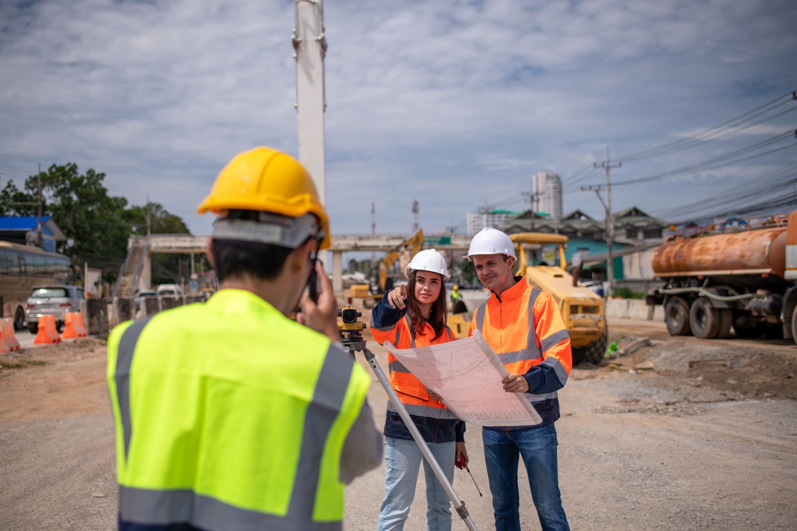 Two engineer surveyors wearing safety uniforms and safety equipment are checking the construction site.