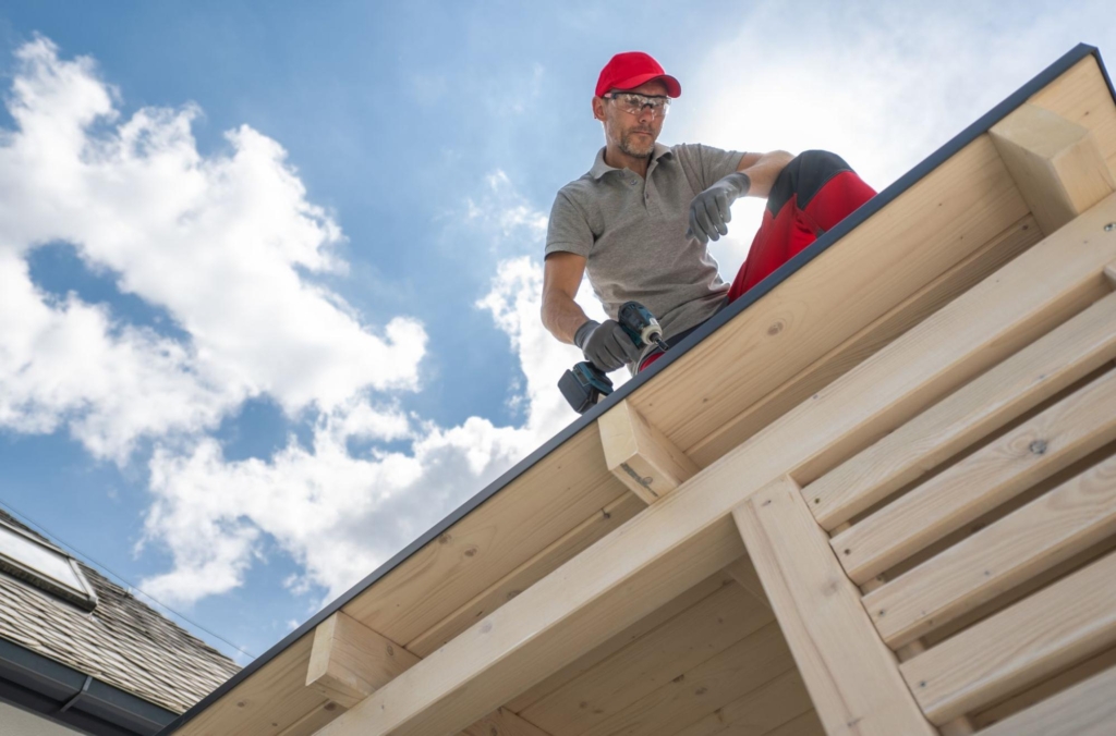 A construction worker drills a part of the roofing.