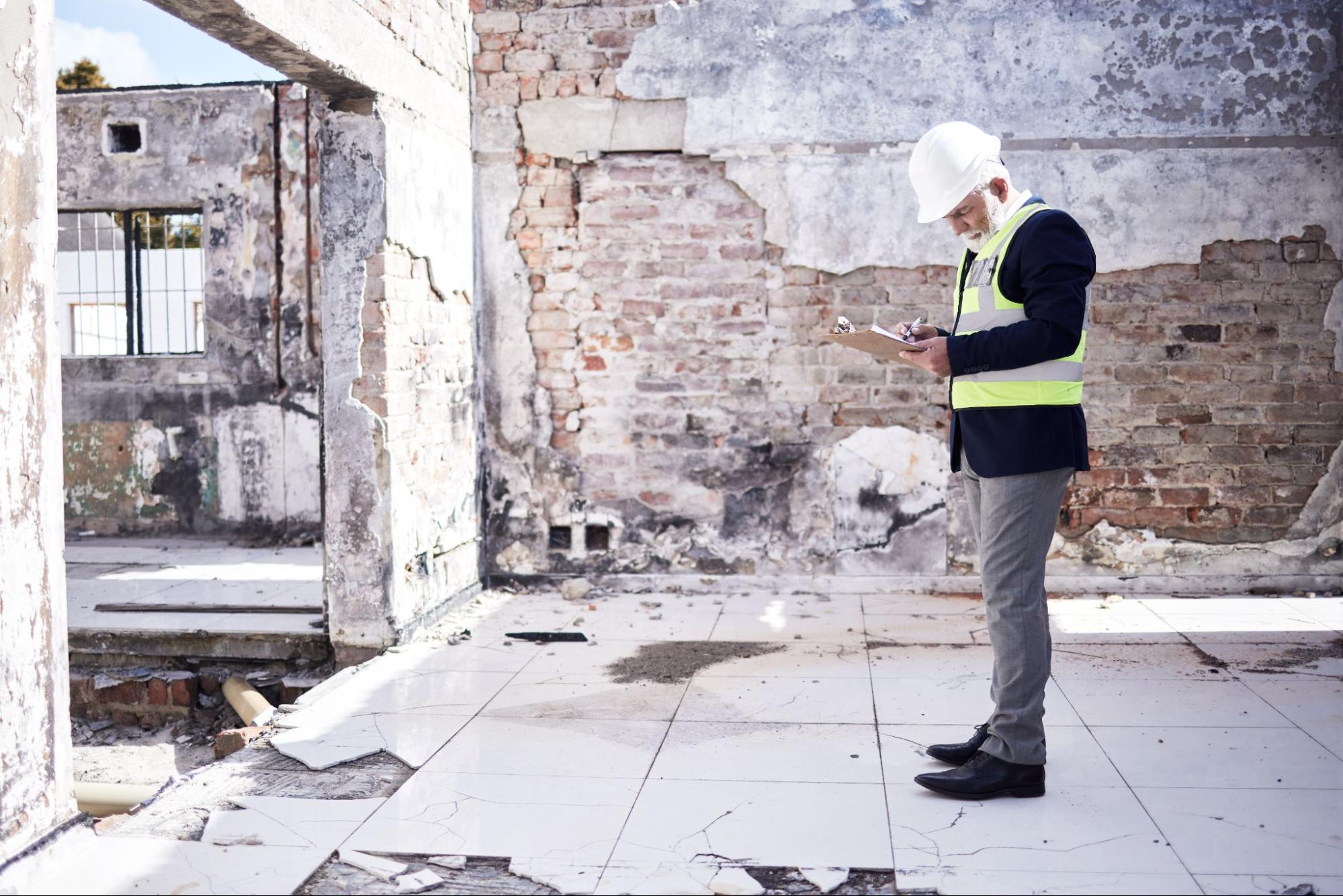 Construction worker assessing damage to a building. 