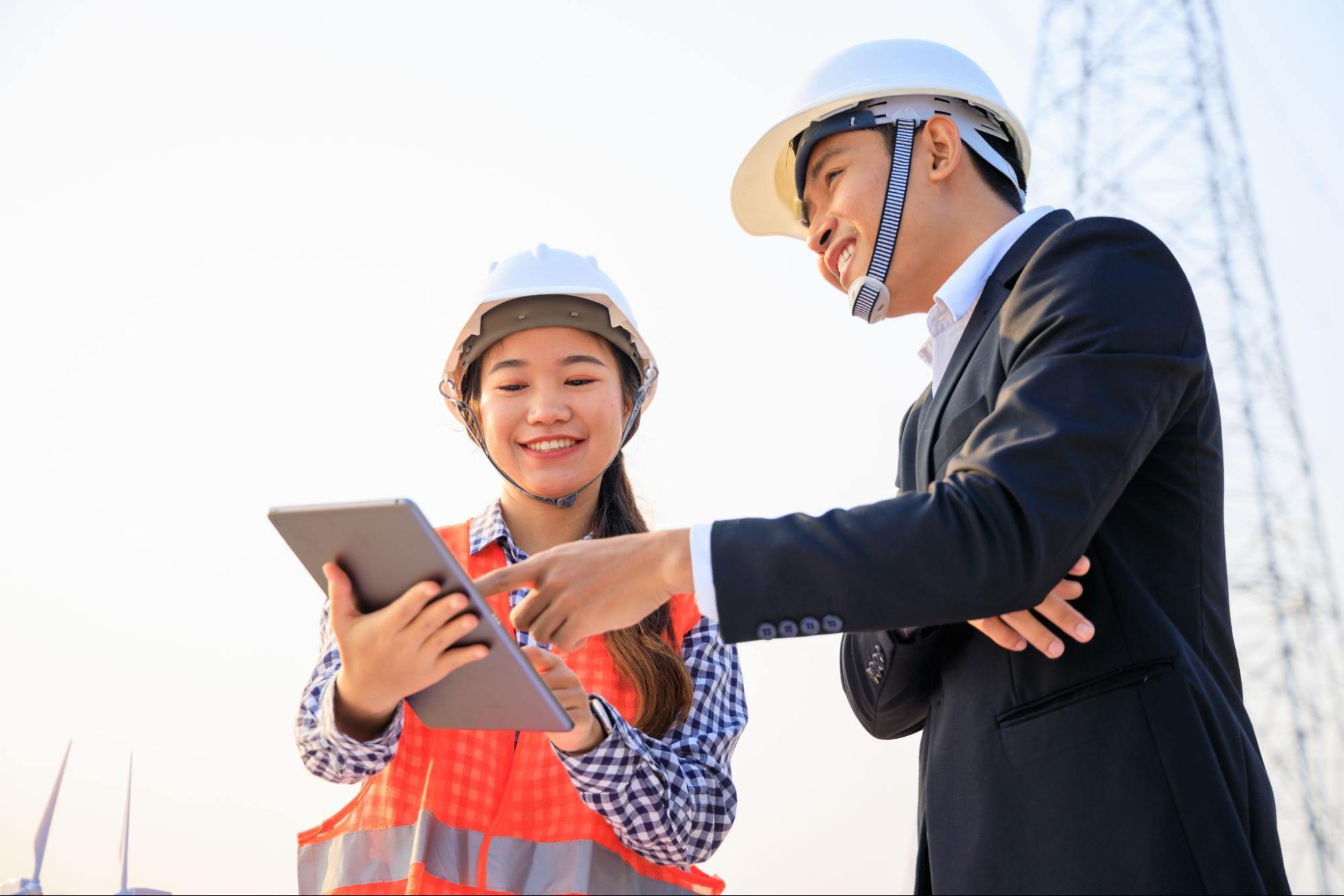 A consultant and a construction manager look at construction plans on an ipad. 