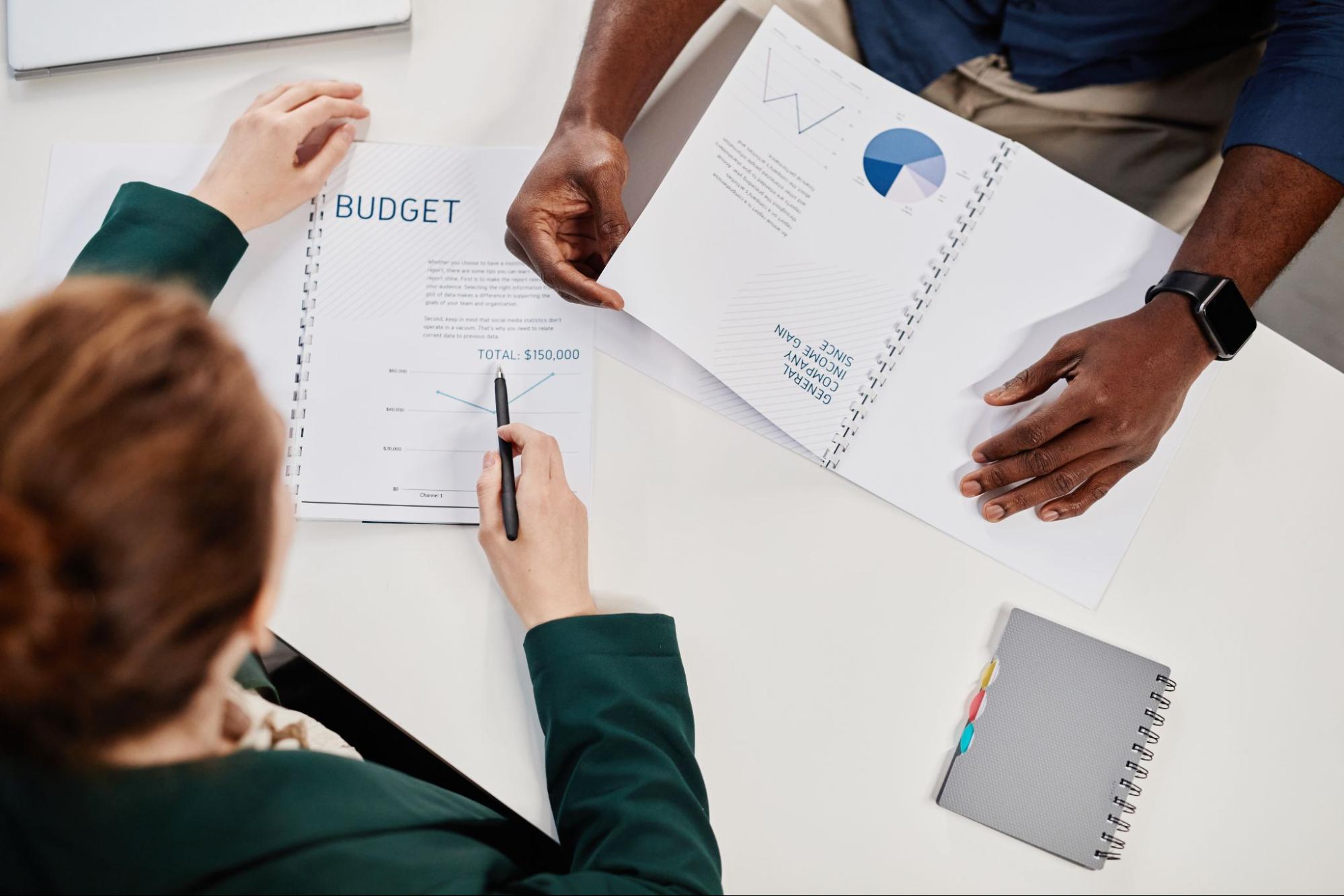 Two people looking at paperwork with the word “budget” at the top. 