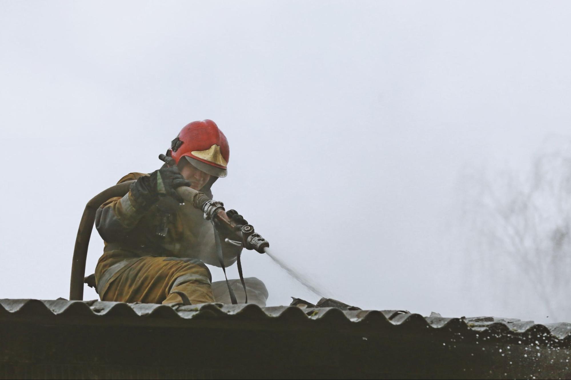 Fireman using a hose on a roof. 