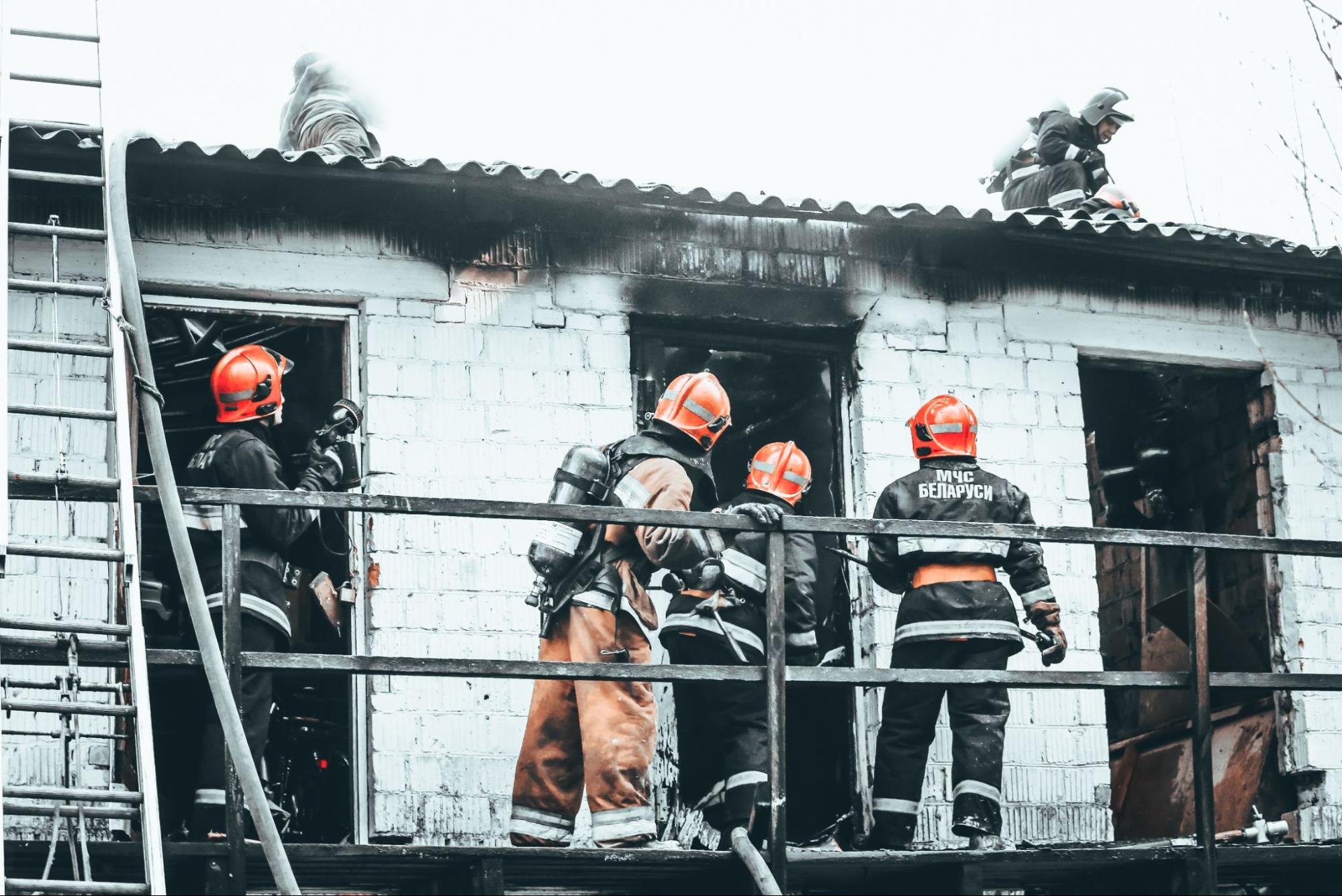 Fire inspectors and restoration professionals in full safety gear inspecting a smoke-damaged building after a fire.